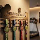 Spartan Race éremtartó oldalról megvilágítva – az acél 2 mm-es vastagsága és falra vetett árnyéka jól látszik