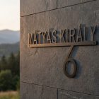 Fém utcanévtábla oldalsó fénnyel megvilágítva, mély árnyékkal a falon