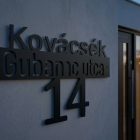 Fém házszámtábla oldalsó megvilágításban, mély árnyékokkal, vastagsága látszik