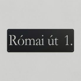 Egy méteres, matt fekete porszórt fém utcatábla fehér vakolatú bejárati falon, lézervágott utcanévvel és házszámmal