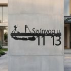 Fém balatonos számtábla felszerelve fa kerítéskapura, nyaraló kert háttérrel