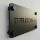 Kész fém cégtábla cégnévvel felszerelve irodai falon, közelkép