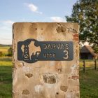 Antracit utcanévtábla farm motívummal – traktor és szélkerék körben, Darvas utca 3 felirattal – régi kőoszlopon, tanya előtt