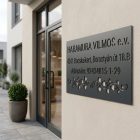 Antracit kültéri cégtábla egy rendelő bejárata mellett, a homlokzaton