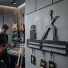 Gitár alakú acél tartó oldalról, éles árnyékkal fehér falon, kiemelve a 2 mm vastagságot